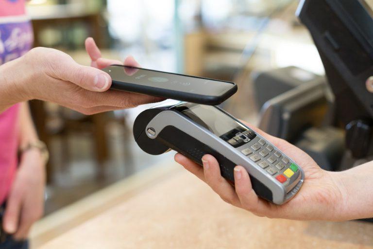 Image of Person Using Phone to Pay at Counter